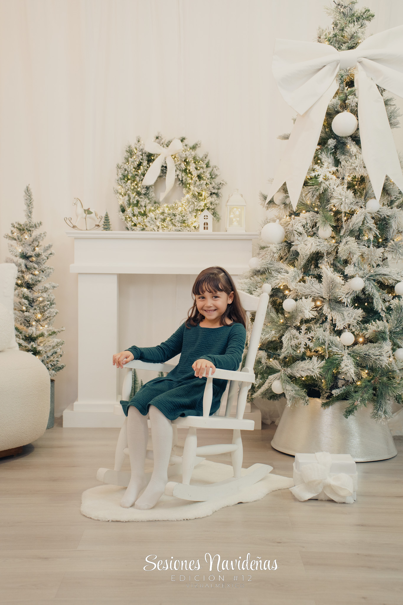 Foto de niña sentada en mecedora infantil junto al árbol de navidad